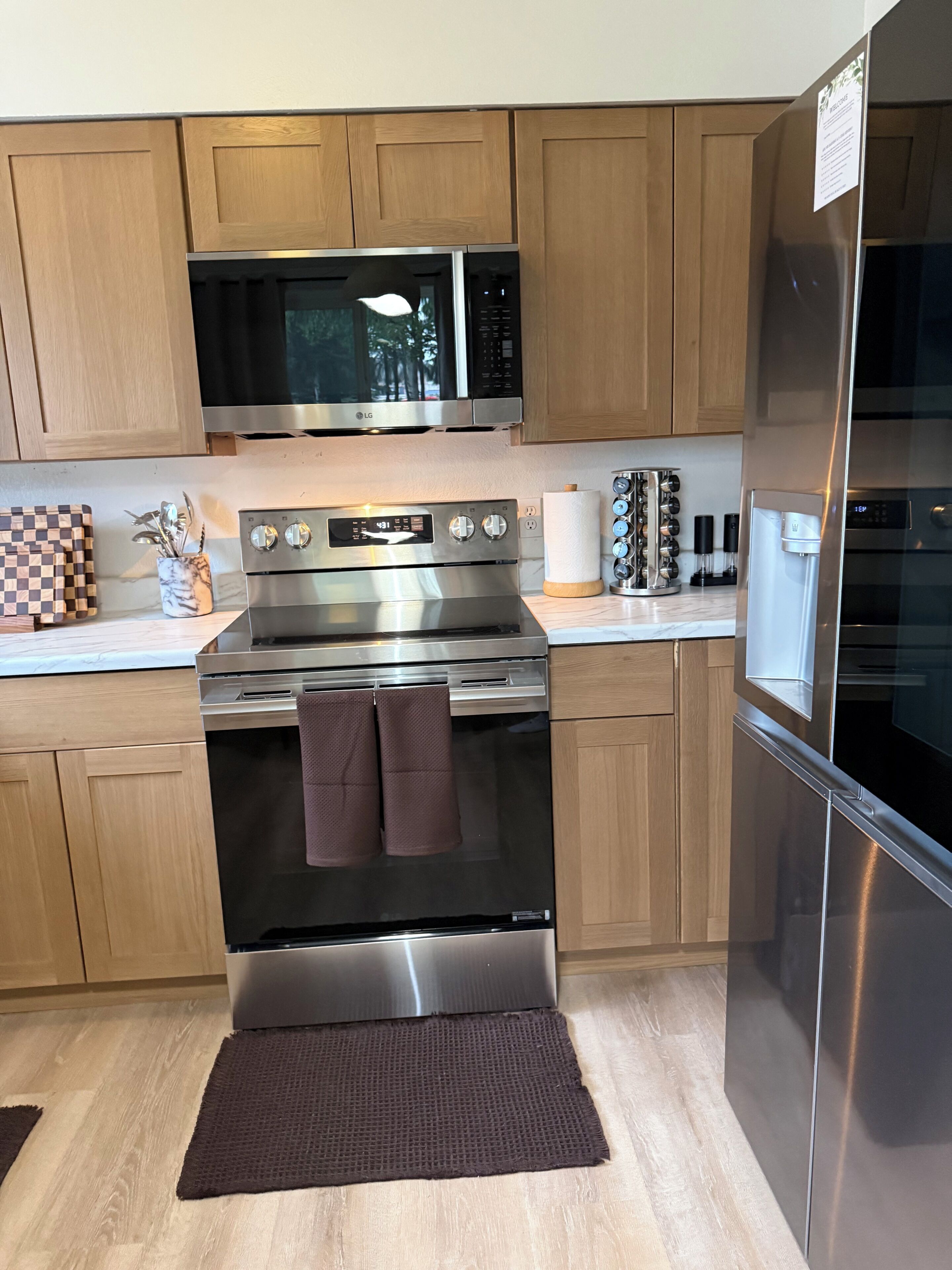 A modern kitchen with stainless steel appliances, wooden cabinets, and a marble countertop.