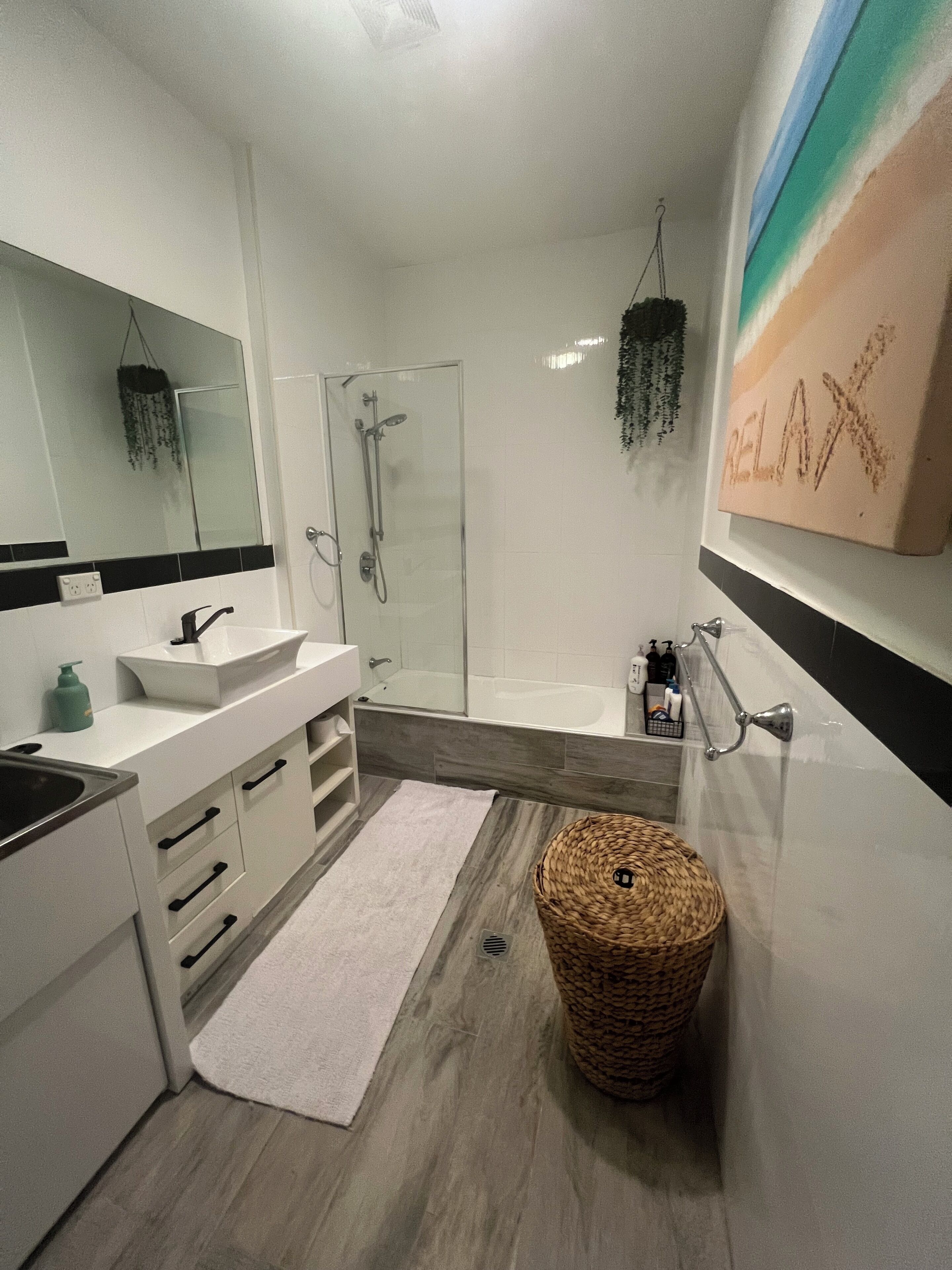 A modern bathroom with a glass-enclosed shower, a white sink, and a large mirror.
