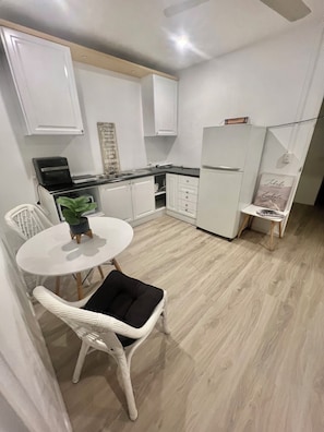 A compact kitchen with white cabinetry, a black countertop, and a white refrigerator.