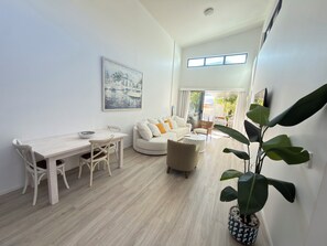 A modern living room with a dining area, a sofa set, and a large potted plant. - Stunning Townhouse opposite Suttons Beach Water views  high ceiling Dual Living (Margate)