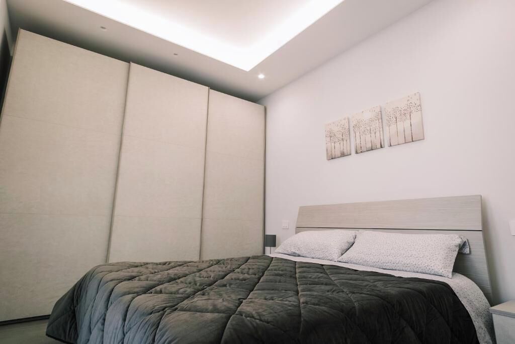 A bedroom with a bed, a nightstand, a wall-mounted artwork, and a sliding door.
