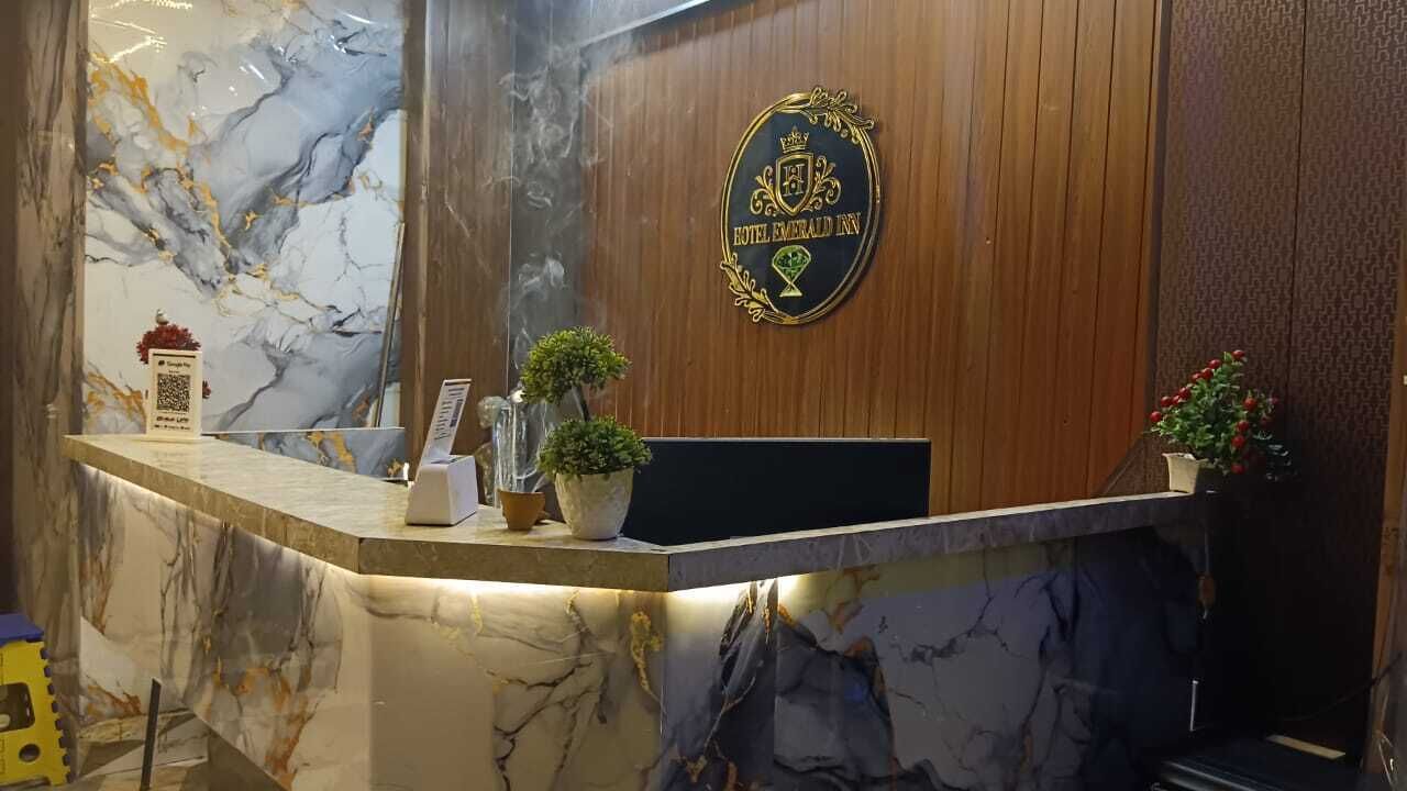 Un taulell de recepció de marbre amb un logotip, un codi QR i plantes en testos.
