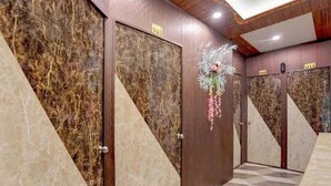 A hotel corridor with marble walls, numbered doors, and a geometric patterned floor.