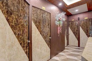 A hotel corridor with marble walls, numbered doors, and a geometric patterned floor.