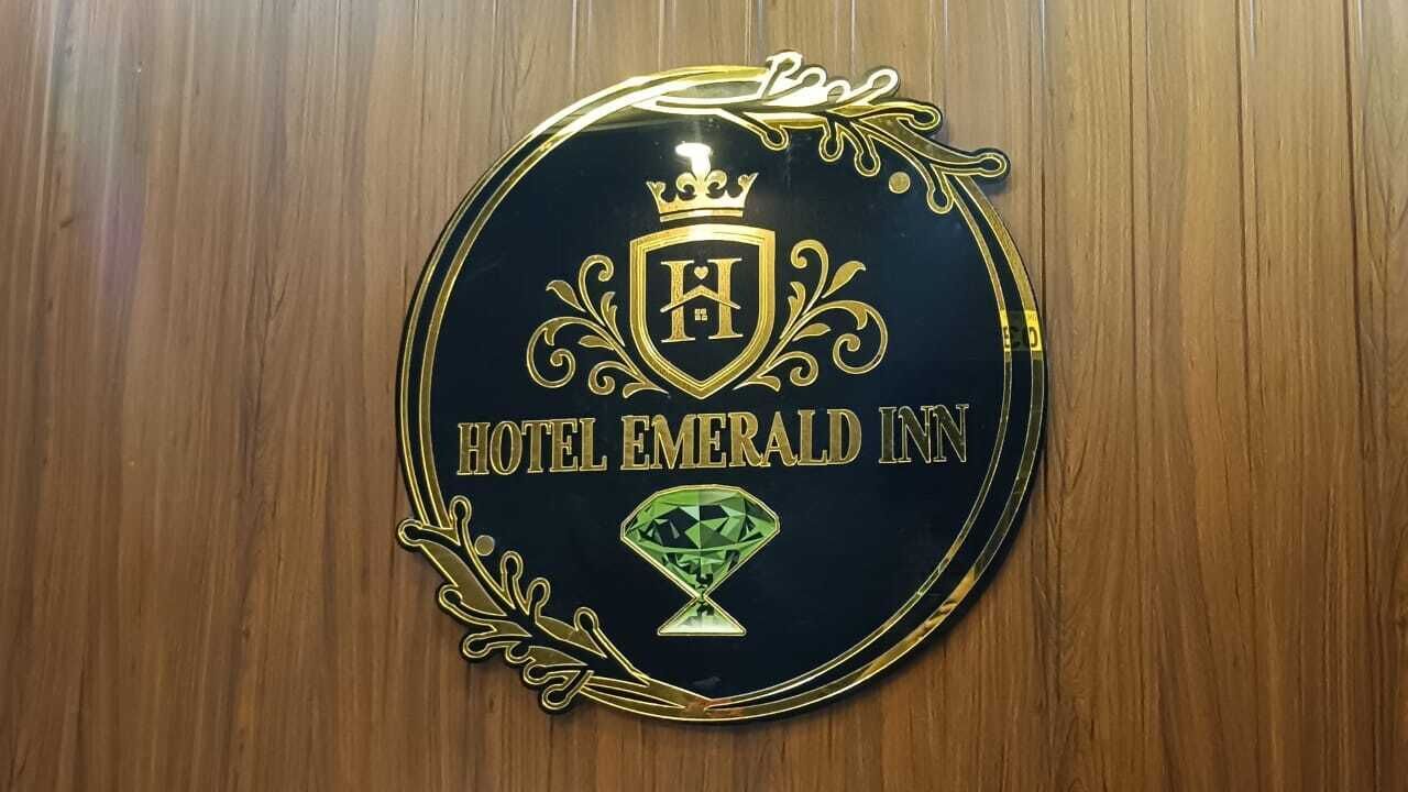 A circular emblem with the text 'HOTEL EMERALD INN' and a diamond-shaped logo.