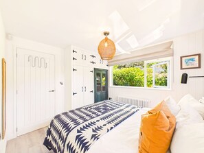 A bedroom with a bed, a wardrobe, a window with a view, and a hanging light fixture.