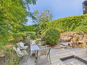 An outdoor patio with wooden furniture and a stone wall. - Bossava Chalet | Cosy Retreat | 2 Bedroom (Lamorna)