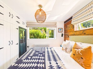 A bedroom with a bed, wardrobe, and a view of greenery outside. - Bossava Chalet | Cosy Retreat | 2 Bedroom (Lamorna)