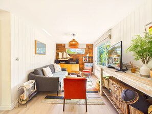 A cozy living room with a sofa, a red chair, a television, and a wooden wall. - Bossava Chalet | Cosy Retreat | 2 Bedroom (Lamorna)