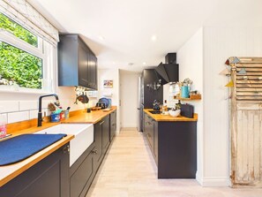 Une cuisine moderne avec des meubles de couleur sombre, des plans de travail en bois et un îlot central.