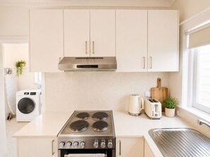A modern kitchen with a built-in stove, a washing machine, and a toaster.