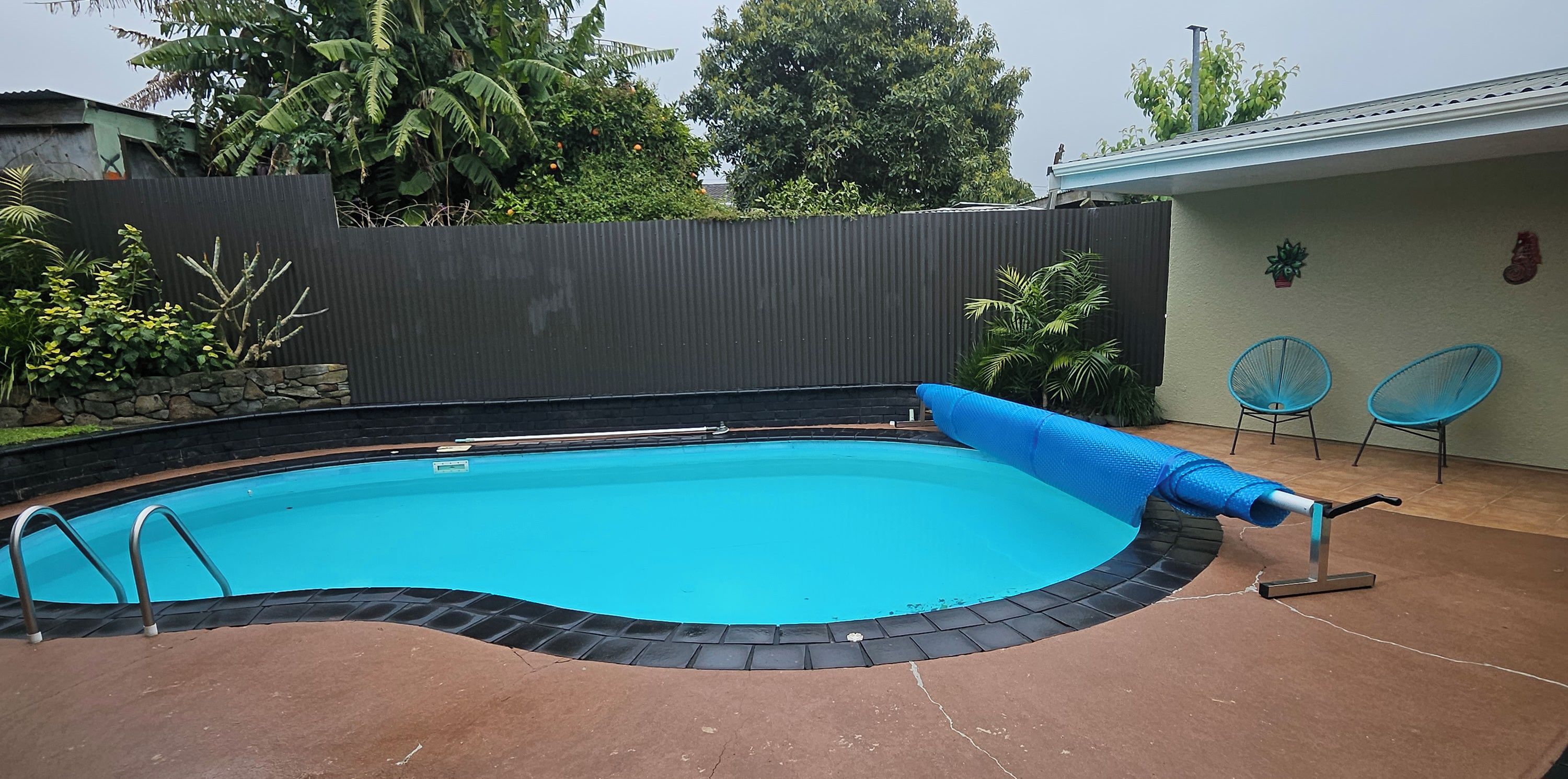 Una piscina con una cubierta azul, una escalera y un borde con baldosas.