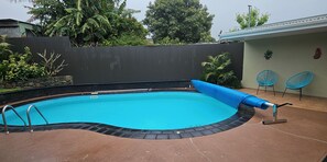 Una piscina con una cubierta azul, una escalera y un borde con baldosas.