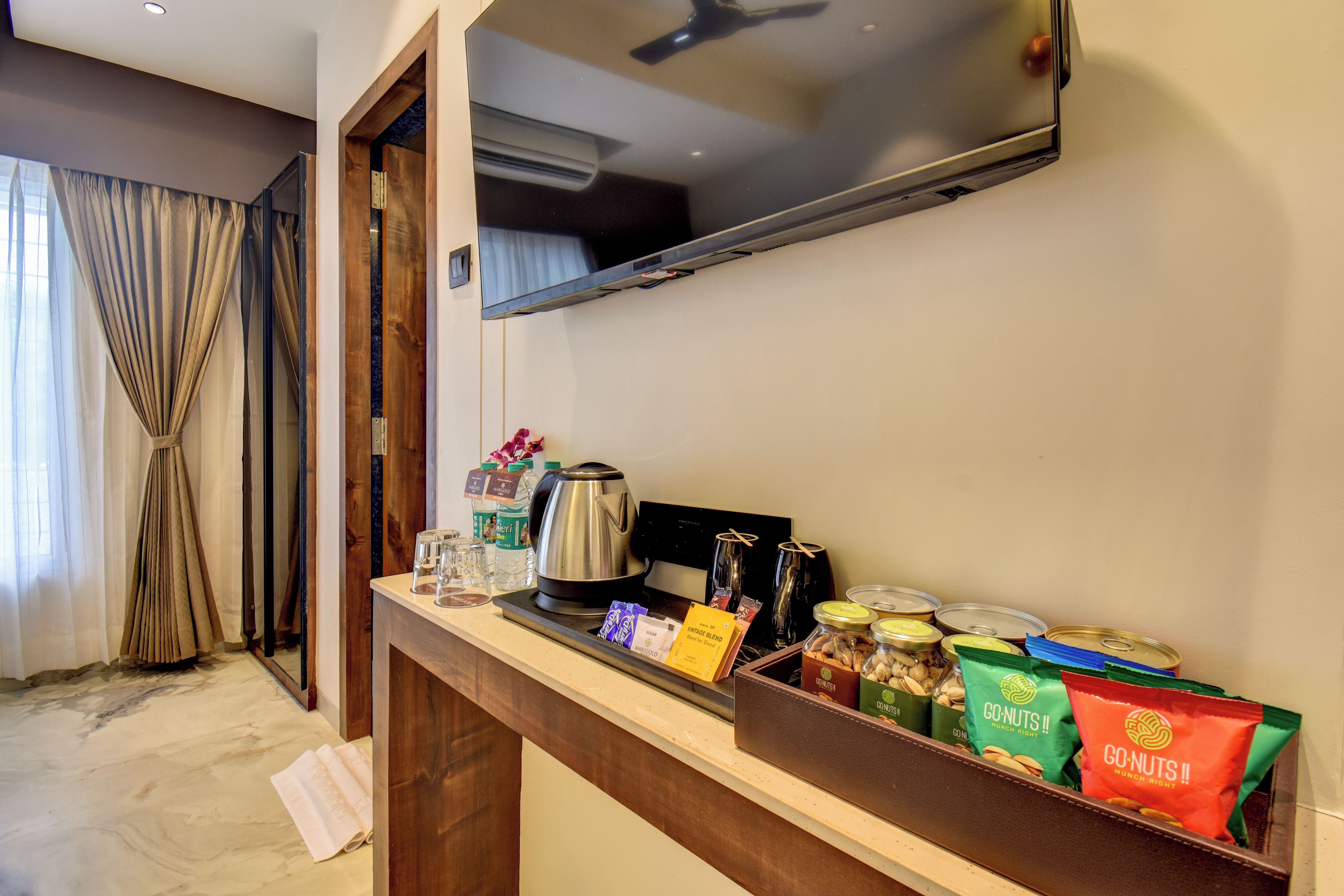 Habitació d'hotel amb minibar, televisió i finestra amb cortines.