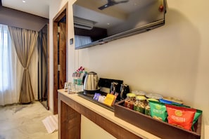 A hotel room with a minibar, a television, and a window with curtains. - Hotel Orchid by Marigold, Shirdi - Premium Comfort Near Sai Baba Temple (Rahata)
