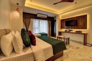 A modern hotel room with a bed, a desk, a flat-screen TV, and an air conditioning unit. - Hotel Orchid by Marigold, Shirdi - Premium Comfort Near Sai Baba Temple (SHIRDI MAHARASHTRA)