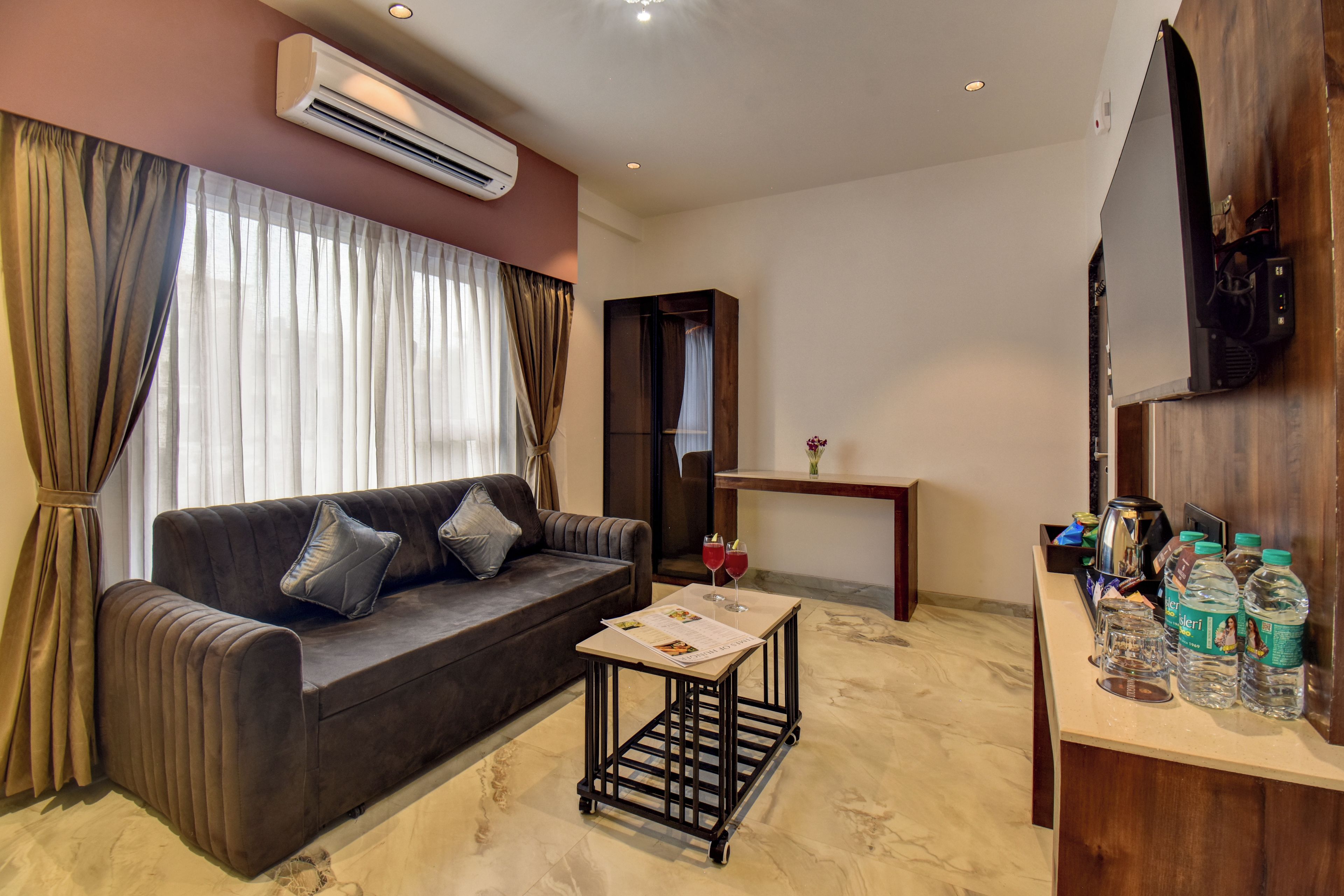 A modern living room with a dark brown sofa, a small coffee table, and a flat-screen TV mounted on the wall.