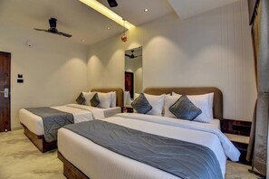 A hotel room with two beds, a ceiling fan, and a mirror. - Hotel Orchid by Marigold, Shirdi - Premium Comfort Near Sai Baba Temple (SHIRDI MAHARASHTRA)