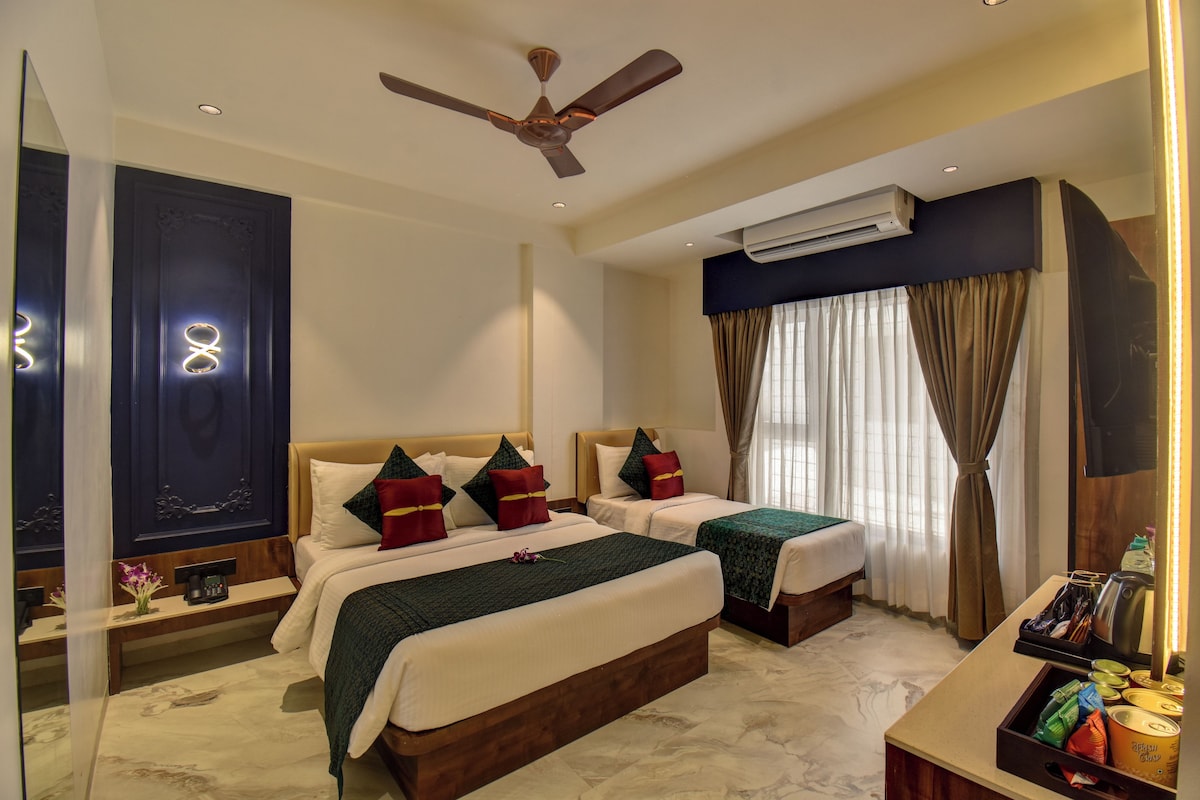 Une chambre d’hôtel avec deux lits, un ventilateur de plafond, un climatiseur, un mini-bar et une vue sur l’extérieur par la fenêtre.