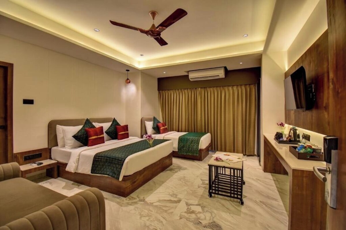 A hotel room with a bed, a desk, a chair, a ceiling fan, and an air conditioning unit.