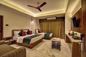 A hotel room with a bed, a desk, a chair, a ceiling fan, and an air conditioning unit. - Hotel Orchid by Marigold, Shirdi - Premium Comfort Near Sai Baba Temple (SHIRDI MAHARASHTRA)
