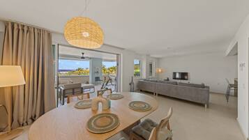 A modern living room with a dining area, a sofa, and a TV.