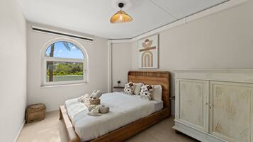 Une chambre à coucher avec un lit, une fenêtre, une armoire et un luminaire suspendu.