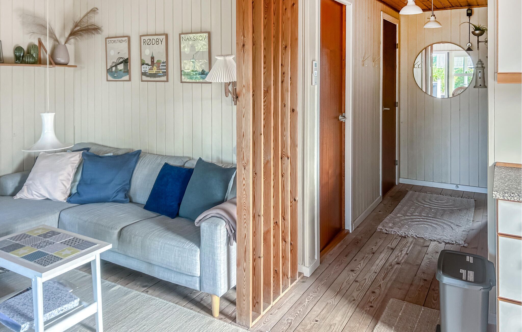 A cozy living room with a grey sofa, a small table, and a wooden door leading to another room.