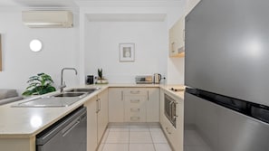 A modern kitchen with a stainless steel refrigerator, a built-in oven, a sink, and a countertop. - Two Bedroom Resort Apartment Near Four Mile Beach | Ivy Pearl Apartment (Port Douglas)