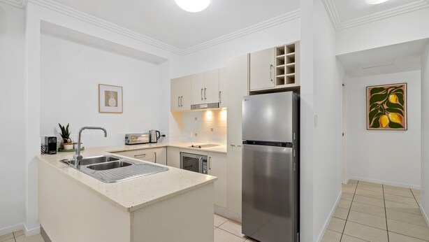 A modern kitchen with a stainless steel refrigerator, a sink, and a countertop. - Two Bedroom Resort Apartment Near Four Mile Beach | Ivy Pearl Apartment (Port Douglas)