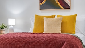 A bed with a red blanket, two yellow pillows, and a beige pillow. - Two Bedroom Resort Apartment Near Four Mile Beach | Ivy Pearl Apartment (Port Douglas)