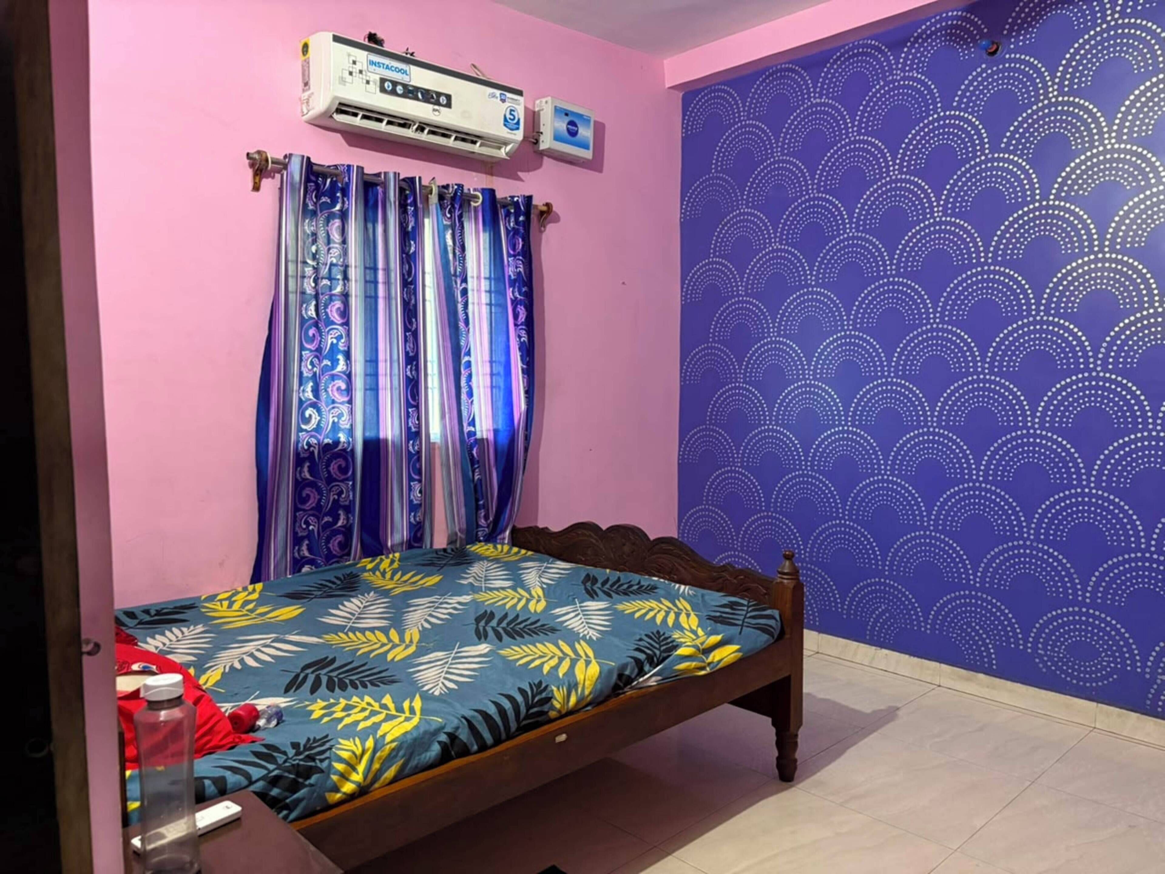 Ein Zimmer mit einem Bett, einer Wandklimaanlage und einer Wand mit Muster.