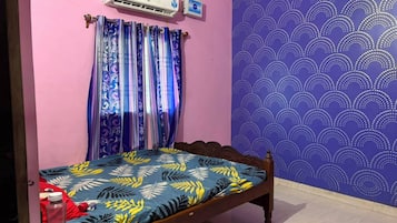 Una habitación con cama, aire acondicionado de pared y pared con diseño.