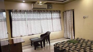 Una habitación con una cama, un escritorio, una silla y un ventanal con cortinas.