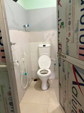 A small bathroom with a toilet, a shower, and a sink.