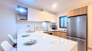 A modern kitchen with white cabinets, a stainless steel refrigerator, and a marble countertop. - Serene Pool View Walk to Fun Beach Dine Shop (Punta Cana)