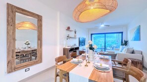 A dining area with a large mirror, wooden table, and chairs. There is a large window with a view of the outdoors. - Serene Pool View Walk to Fun Beach Dine Shop (Punta Cana)
