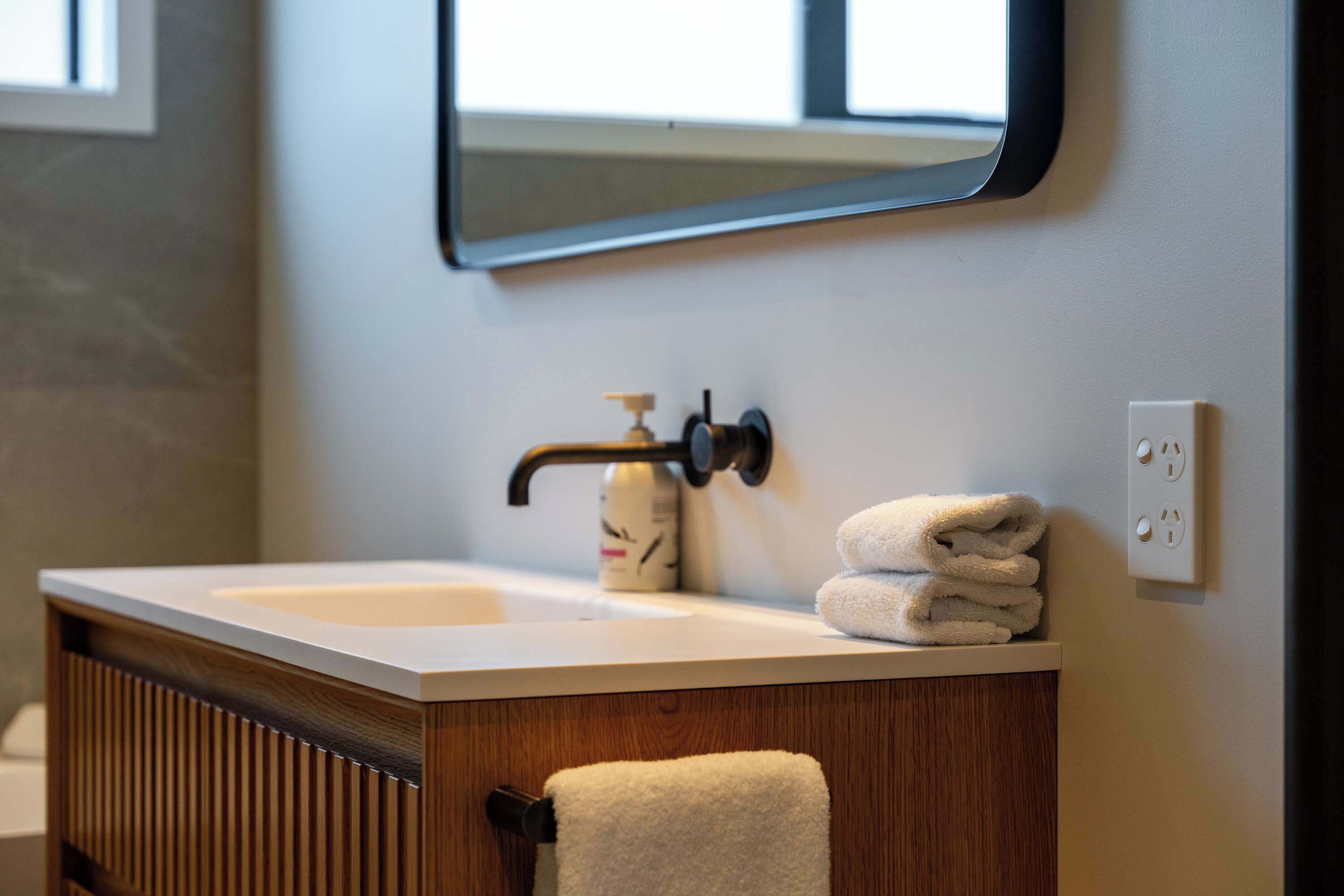 A bathroom vanity with a sink, a soap dispenser, and a towel.
