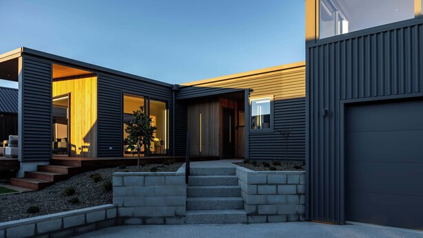 Une maison moderne dotée d’un patio couvert, d’un petit jardin et d’un garage.