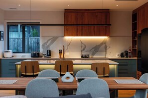 A modern kitchen with a central island, wooden cabinets, and a marble backsplash. - Eliza's Escape with Mountain Views (Wānaka)