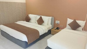 Habitación de hotel con cama, mesita de noche y una pequeña mesa con un teléfono y botellas.