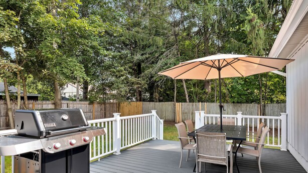 An outdoor deck with a grill, dining table, chairs, and an umbrella. - Oklahoma Breeze | Walk to Track & Downtown | 4BR + Pet Friendly (Saratoga Springs)