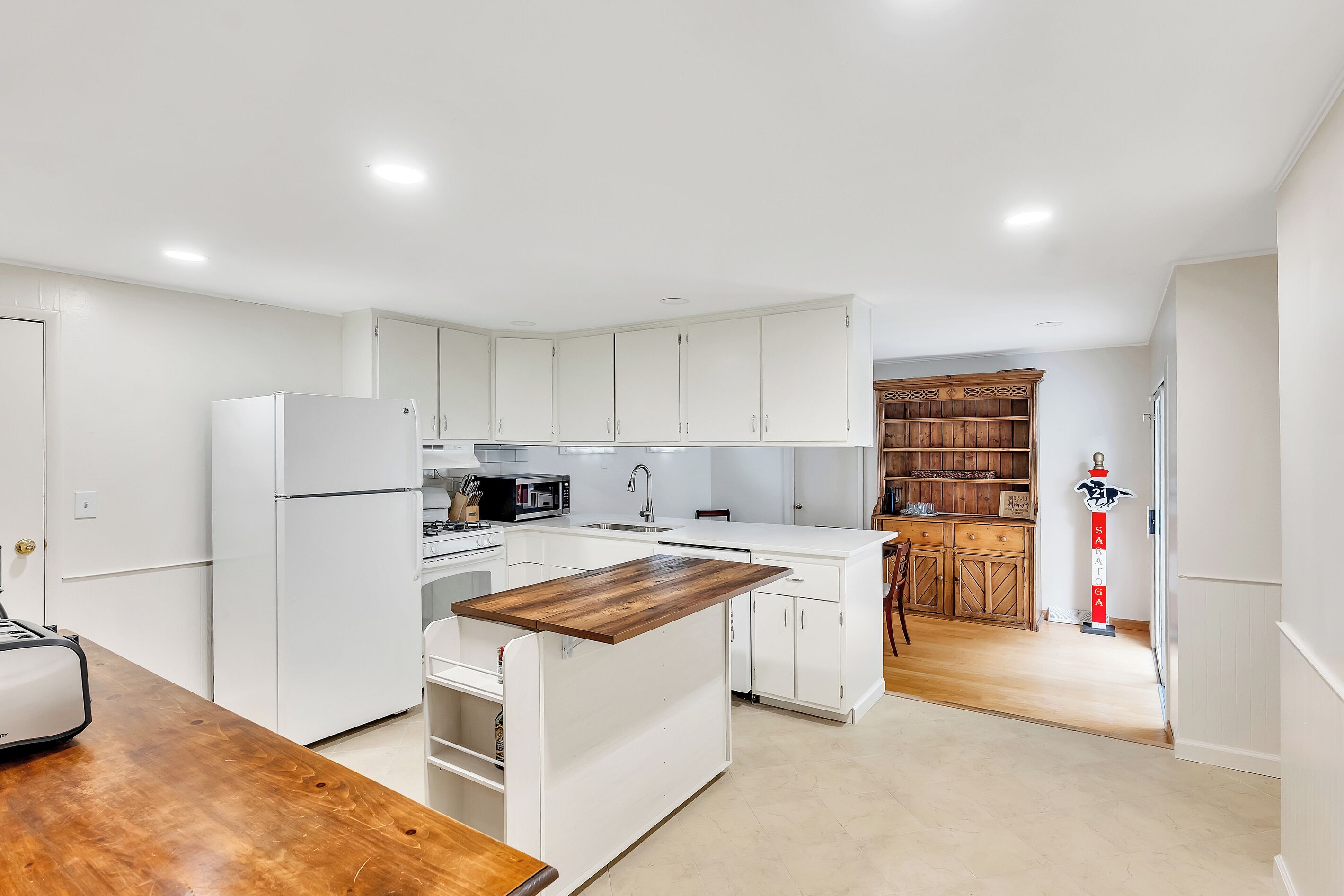 A modern kitchen with white cabinetry, a wooden island, and a built-in oven.