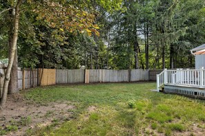 A backyard with a wooden deck, a fenced area, and a variety of trees.