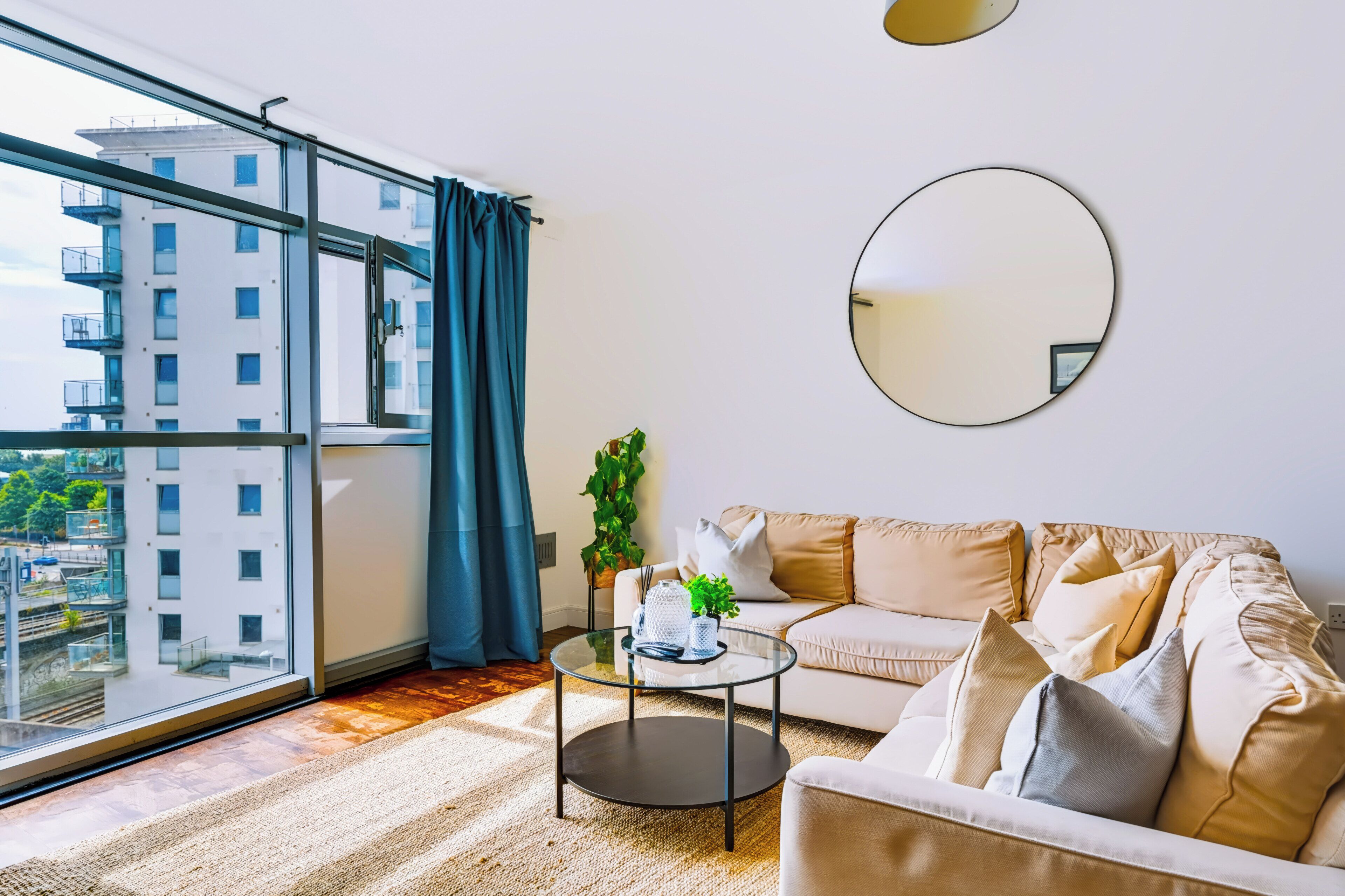 Un salon moderne avec un canapé, une table basse et une grande fenêtre agrémentée de rideaux.
