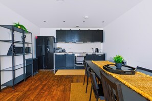 Una cocina moderna con gabinetes negros, horno empotrado y comedor con mesa y sillas.