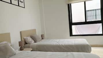 Un dormitorio con dos camas, una ventana con vistas y una pared con una cita inspiradora.