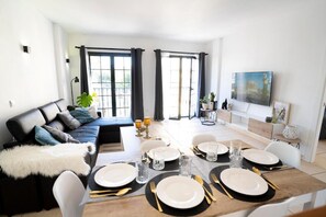 A modern living room with a dining area, large windows, and a flat-screen TV. - Apartamento 'Estrella Del Sur Torremolinos' con vistas a la montaña, Wi-Fi y aire acondicionado (Torremolinos)