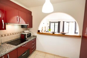 Uma cozinha com armários vermelhos, micro-ondas e janela com vista.