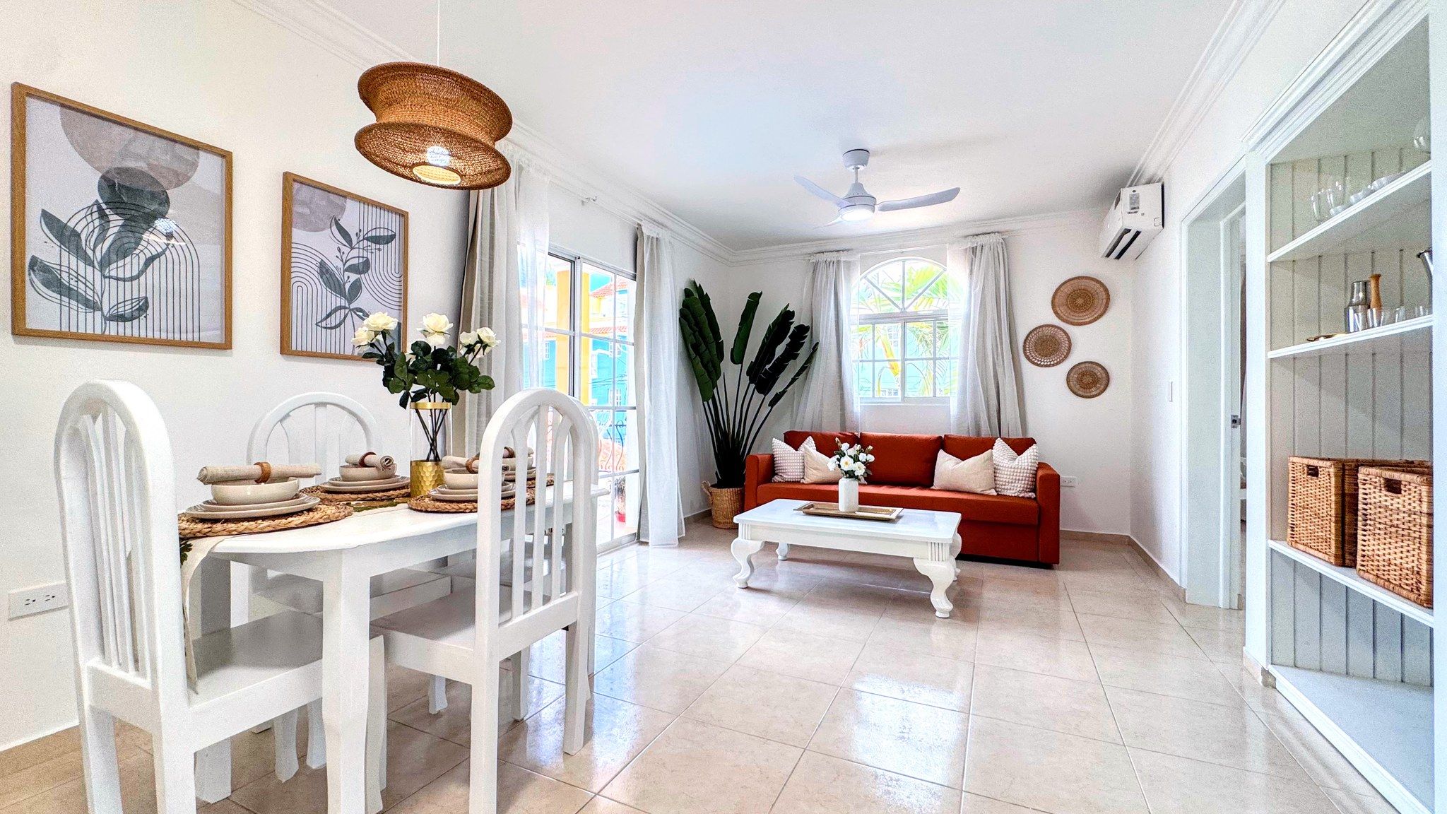 A spacious living room with a dining area, a red sofa, and a white coffee table.